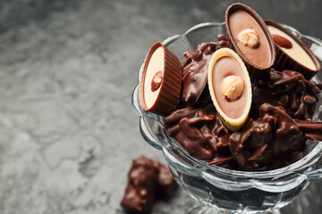 Dessert bowl with tasty chocolate candies on dark background, closeup