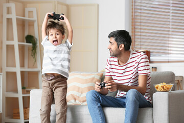 Father and little son playing video games at home