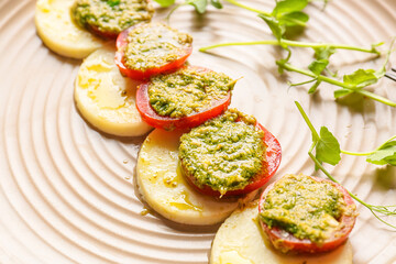 Mozzarella cheese with tomatoes and pesto sauce on plate, closeup