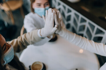 Obraz premium Co-workers in protective masks give a high five in the office.