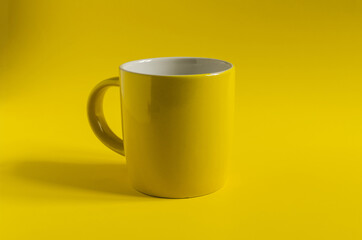 Abstract background yellow ceramic mug on a yellow background close-up, concept.