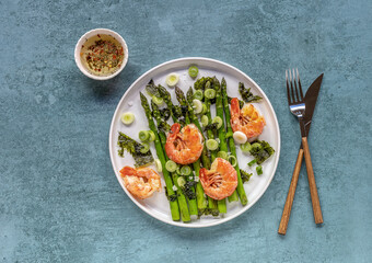 Seasonal salad from prawn shrimp, green asparagus, onion, and seaweed on a plate, festive appetizer, or buffet snack. Clean healthy eating.