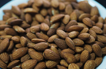 Dried brown toasted almonds nut inside white plate, Vegetarian meal, Healthy eating ready for eat