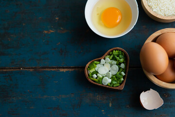 Multiple eggs in a cup with garlic and onions lay on a vintage wooden floor.