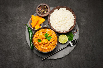 Plate of Traditional Chicken Curry, nachos and rice on stone serving board