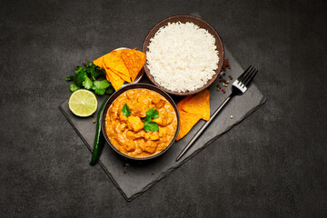 Plate of Traditional Chicken Curry, nachos and rice on stone serving board