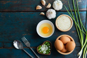 Multiple eggs in a cup with garlic and onions lay on a vintage wooden floor.