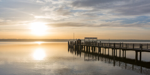 Fototapeta na wymiar Sunset at Ammersee (Lake Ammer). With wooden main pier of Herrsching.