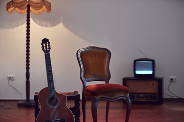 Acoustic guitar with retro vintage furniture at home.