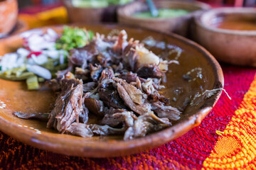 Mexican chopped lamb meat, hot sauces, and lime slices in clay bowls