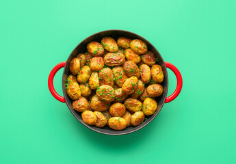 Roasted baby potatoes in a pan, top view on a green background.
