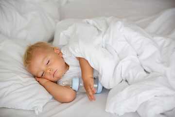 Fototapeta na wymiar Cute little baby boy, sleeping with bottle with formula milk