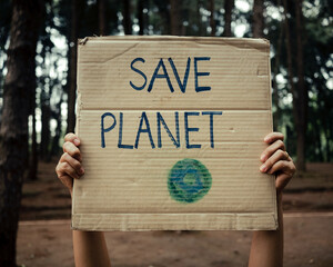 Hand holding banners protesting over pollution and global warming in the forest to save planet...