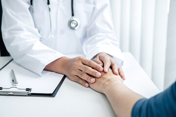 Doctor holding hands on patient about bad news at consulting room