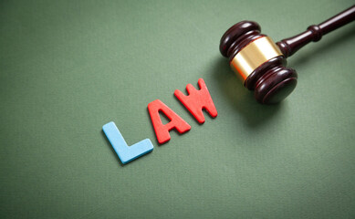 Word Law and judge gavel on green background.