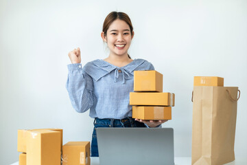 Asian woman small business owner standing and smiling to raise arm when job finished after receive order