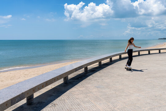 Young asian women riding surfskate board. Trendy outdoor sport in Thailand, Asia.