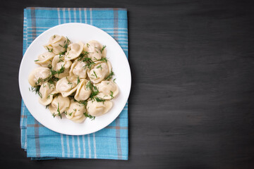 Meat dumplings - Russian dumplings, dumplings with meat on a plate on a black background