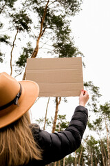 Female hands standing with cardboard outdoors. Nature background. Copy space for text. Protester...
