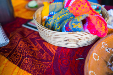 Artisanal tortilla napkin in basket above red and orange tablecloth