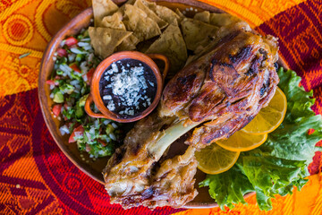 Roasted meat with vegetables and refried beans on colorful tablecloth