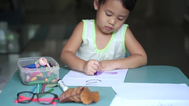 Litte Thai girl drawing at table.