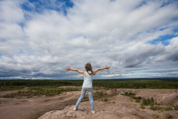 Obraz premium Little child girl embracing world universe against sky clouds outdoors