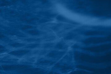 Trendy blue colored low contrast abstract background with light and shadows caustic effect. Light passes through a glass. Water background. 