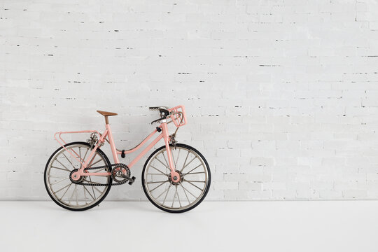 World bicycle day concept. Pink bicykle on white brick wall. 3 june.
