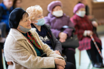 Fototapeta na wymiar A group of elderly people wearing medical masks at a meeting or at a nursing home during a coronavirus epidemic.