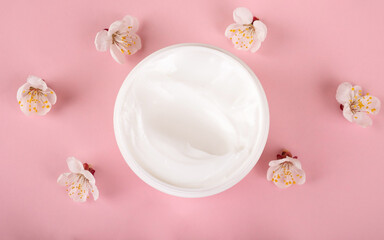 Fototapeta na wymiar cream and flowers on pink background,beauty skin care cosmetic.