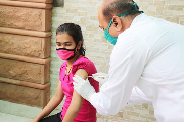 Vaccination in india, Medical worker or doctor giving vaccine injection to a young girl at hospital...