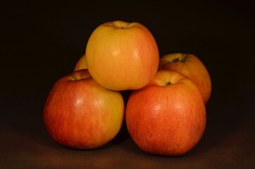 Photographed and red apples on a dark background, lying on a wooden dark brown table.