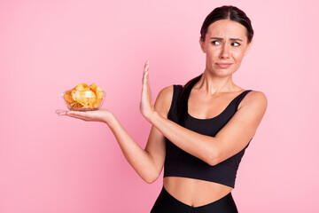 Photo of unsure upset young woman dressed sportive not want eating potato crisps isolated pink color background