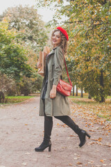 Autumn portrait of happy beautiful woman in red french beret and handbag outdoor