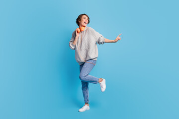 Obraz premium Full length body size view of attractive cheerful girl listening music dancing isolated over bright blue color background