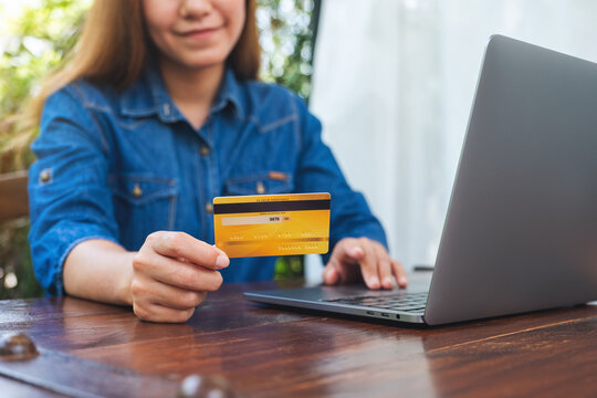 Closeup image of a woman holding credit cards while using laptop computer for online shopping