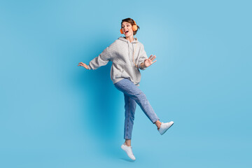 Fototapeta na wymiar Full length photo portrait of girl kicking jumping up with headphones isolated on pastel blue colored background