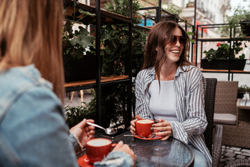 Two Young Women Drinking Coffee in Cafe Outdoors, Lunch Time Concept, Brunette Girl in Focus