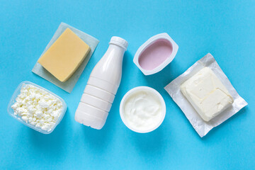 Flat lay of dairy products. Milk, curd, sour cream, cheese and butter on blue background, top view