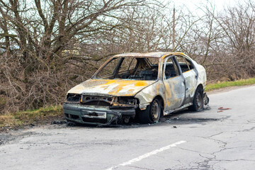 Burned car after an accident on the asphalt road. Front view. Arson of a car, criminal showdowns