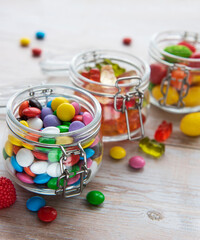 Colorful candies in jars on table