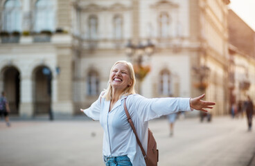Fototapeta premium Happy woman with outstretched arms on the street.