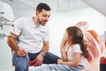 Obraz premium Little girl visiting male dentist in clinic. Conception of stomatology