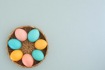 Minimalistic Easter background with pastel Easter eggs on a light blue background with place for text. Flat lay, top view. Easter spring holiday concept