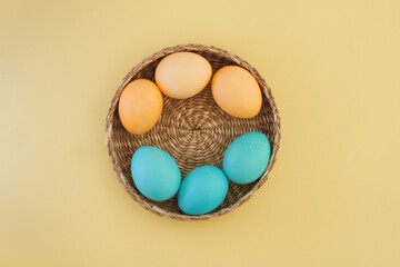 Easter composition with multi-colored Easter eggs in pastel yellow and blue colors on a yellow background. Flat lay, top view