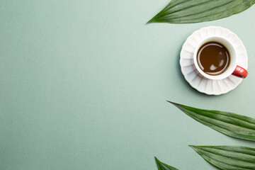 Cup of coffee with green leaf on green background. flat lay, top view, copy space