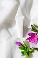 cosmetic cream on a light textile background with pink flowers. Concept of gentle skin care, copy space