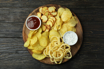 Tray with different snacks on wooden background