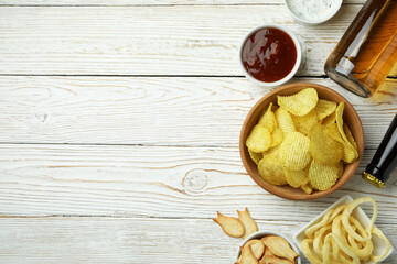 Different snacks, beer and sauces on white wooden background